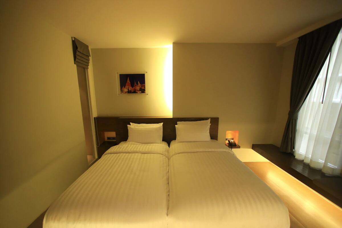 A double bed with a wooden headboard, a bedside table with a lamp, and a painting on the wall.