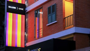 A building with a sign that reads "SILOM ONE" and a colorful vertical light display. - Silom One (Bangkok)