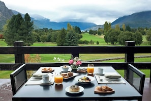 A table set with breakfast items and a view of a mountainous landscape.