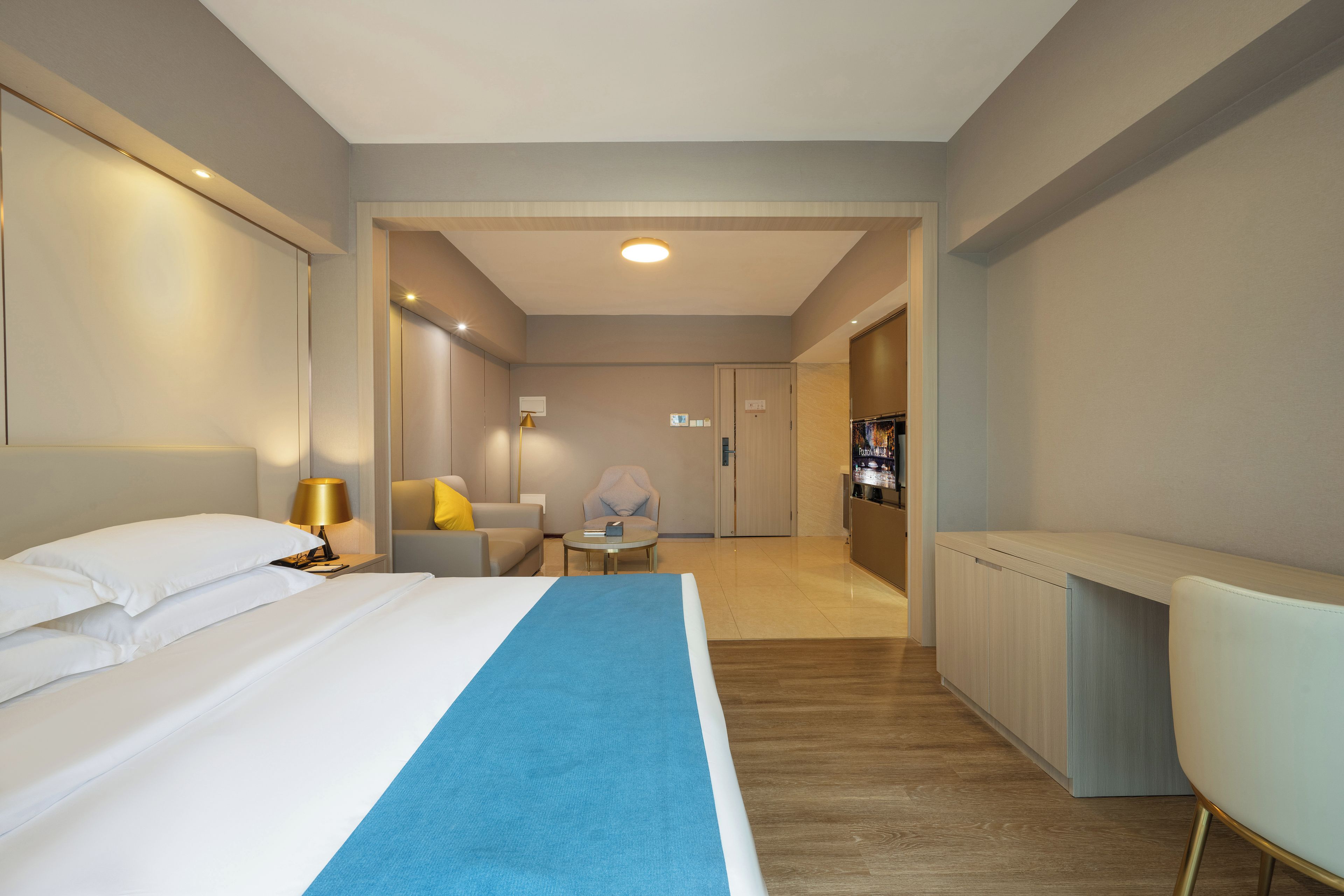Una habitación de hotel con una cama, un escritorio, una silla, un televisor y una puerta que da a otra habitación.