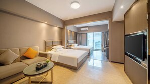 Habitación de hotel con sofá, dos camas, televisión y mesa de centro.