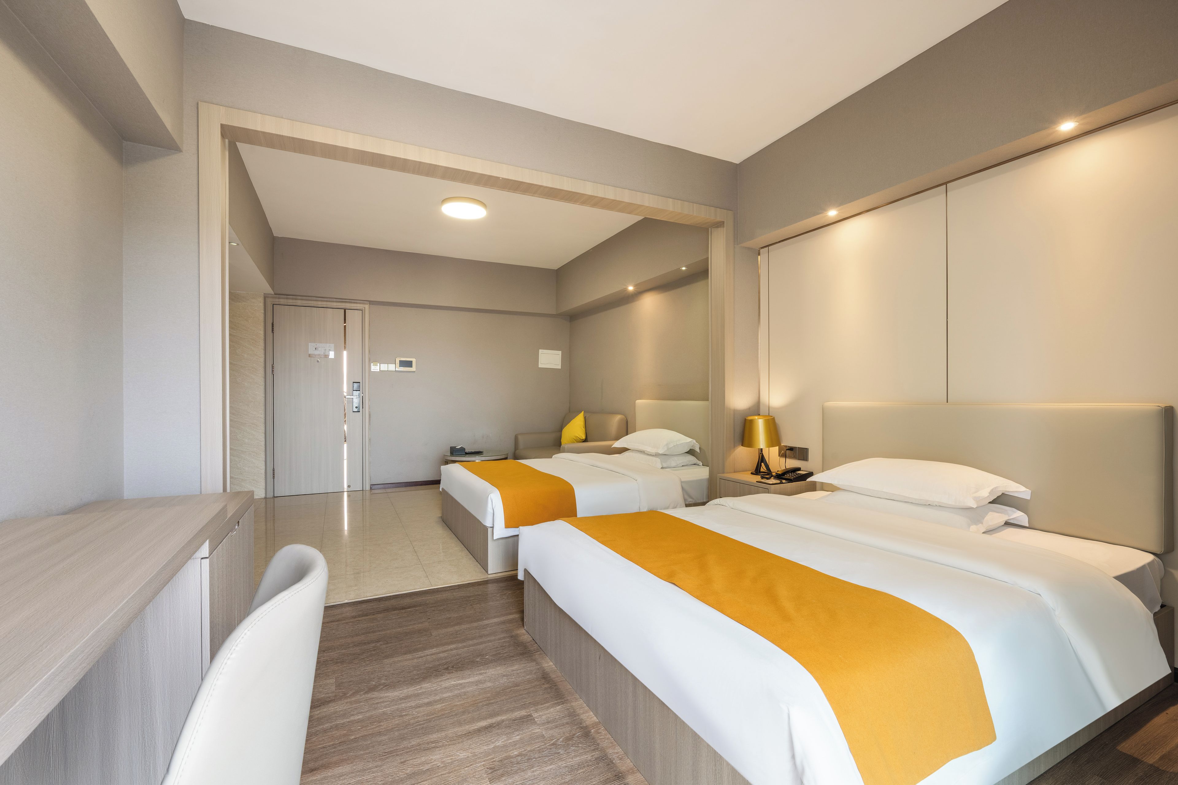A hotel room with two beds, a desk, and a chair.