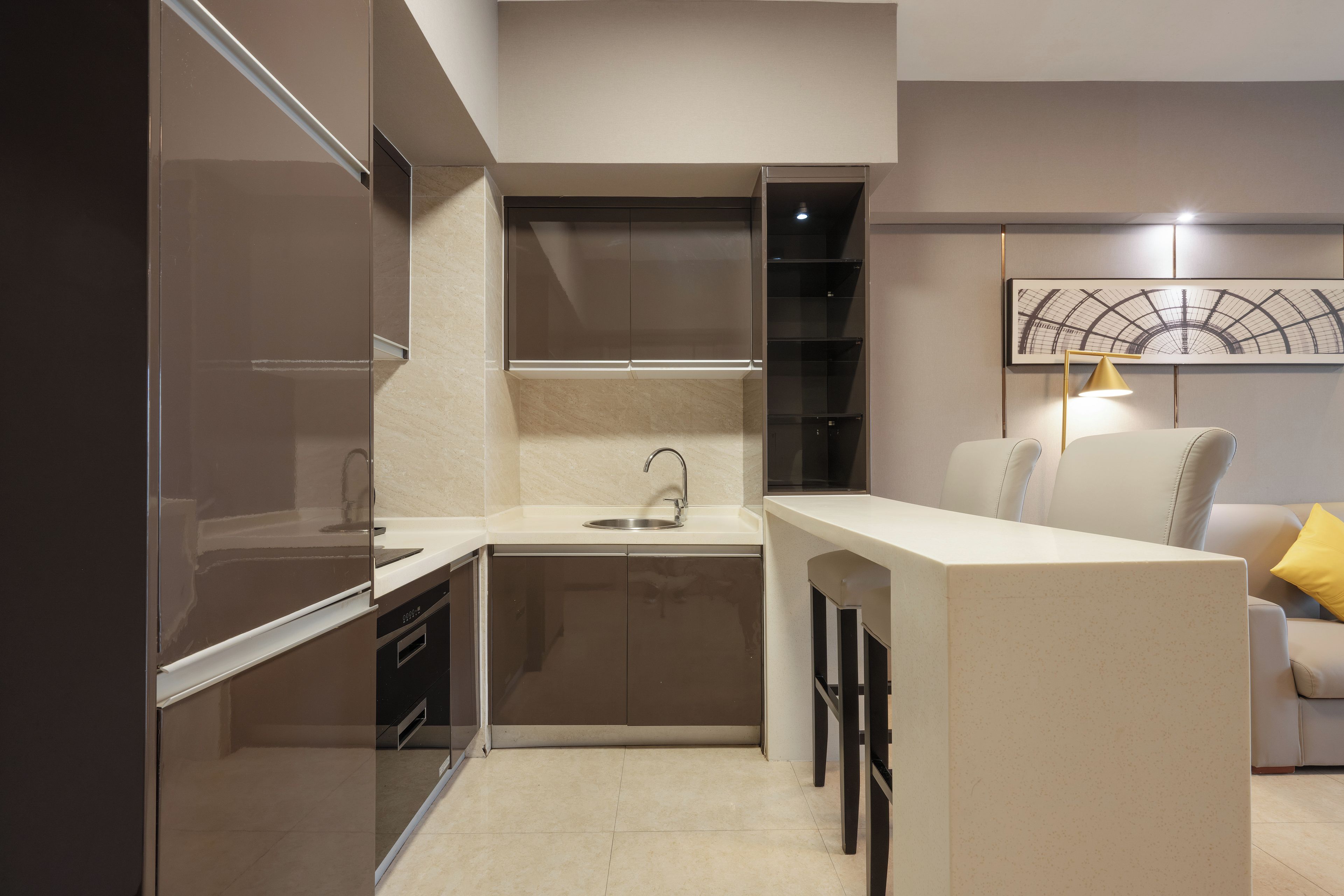 Una cocina compacta con un lavamanos integrado, un pequeño comedor con sillas y una lámpara fijada a la pared.