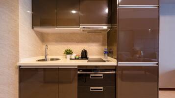 A modern kitchen with a built-in dishwasher, stainless steel cabinets, and a countertop with a sink, kettle, and potted plant.