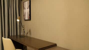 Un escritorio con una silla, una lámpara y un cuadro en la pared.