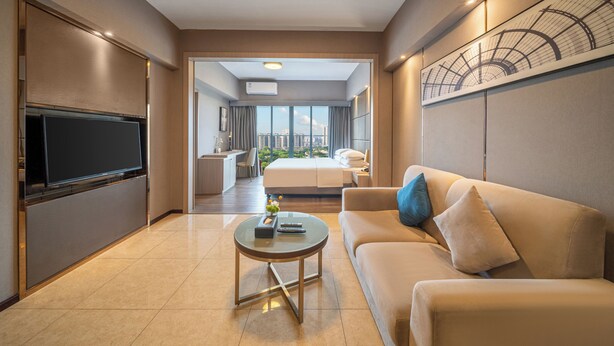 Una habitación de hotel moderna con televisión de pantalla plana, un sofá, una mesa de centro y una cama grande.