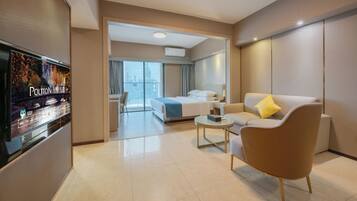 A modern hotel room with a bed, a sofa, a coffee table, and a TV.