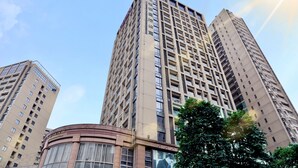Un edificio de gran altura con varios pisos y un núcleo central, rodeado de otros edificios altos.