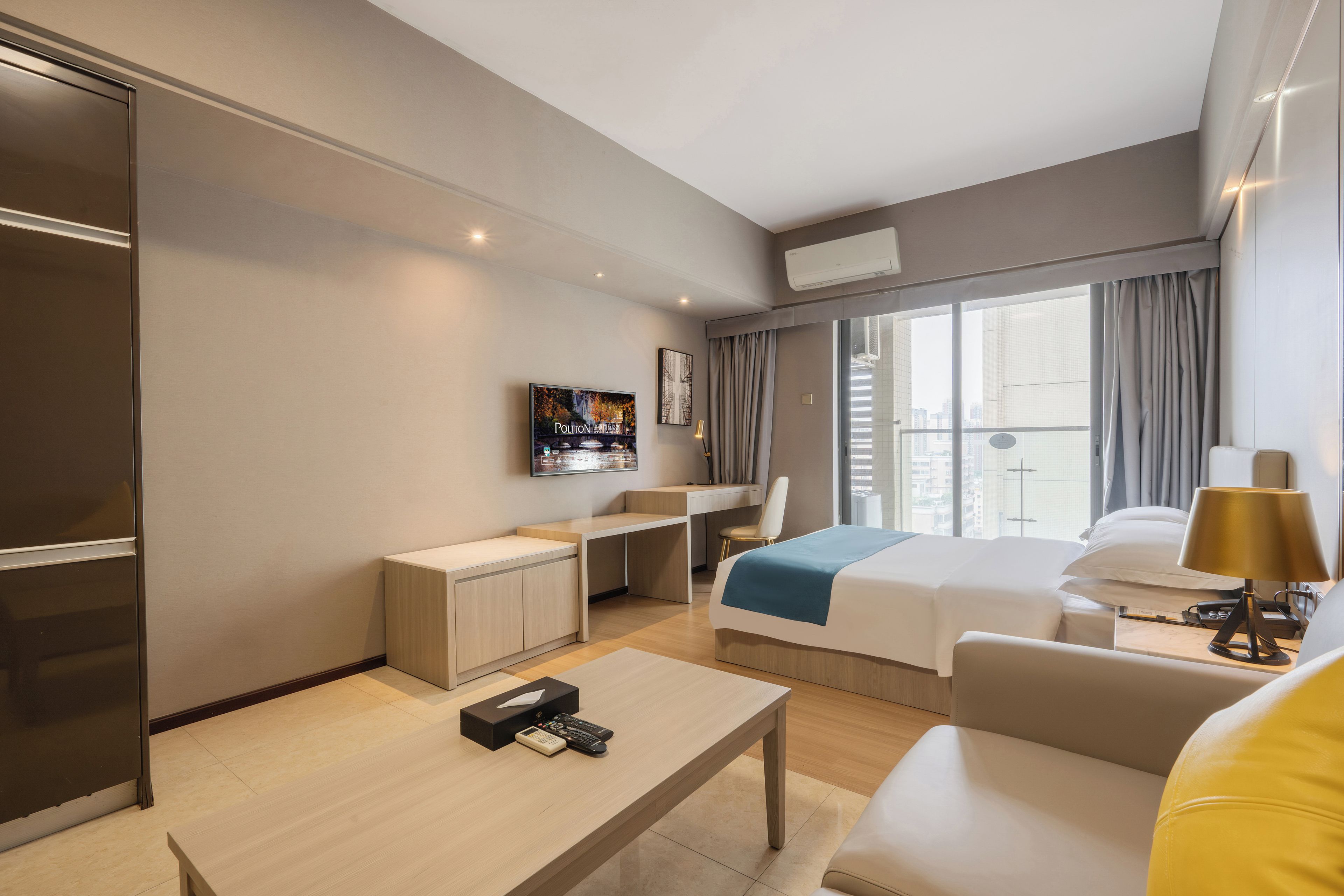 Una moderna camera d'albergo con un letto, una scrivania, una televisione e una finestra con tende.