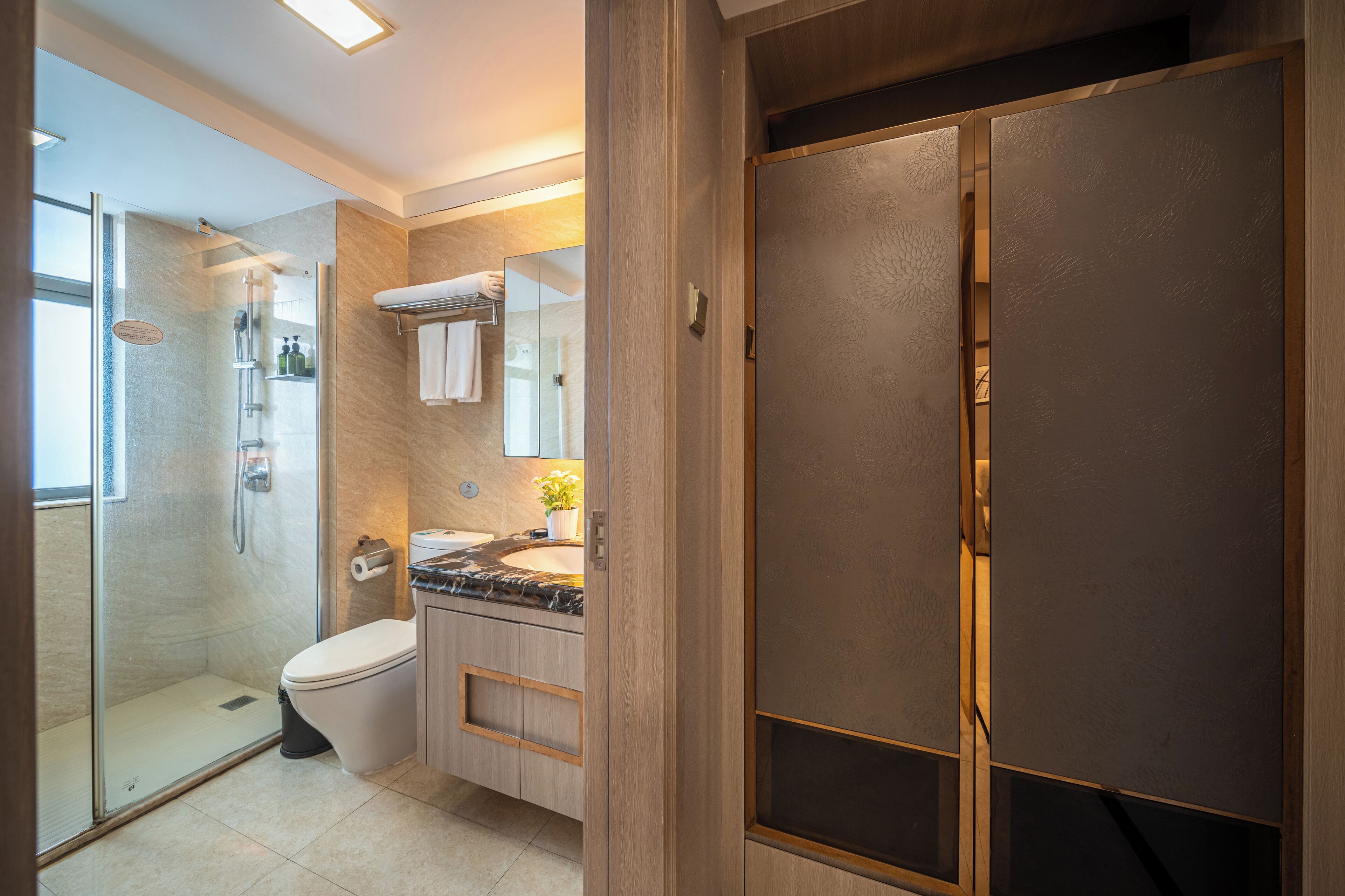 A modern bathroom with a glass-enclosed shower, a toilet, and a vanity with a marble countertop.