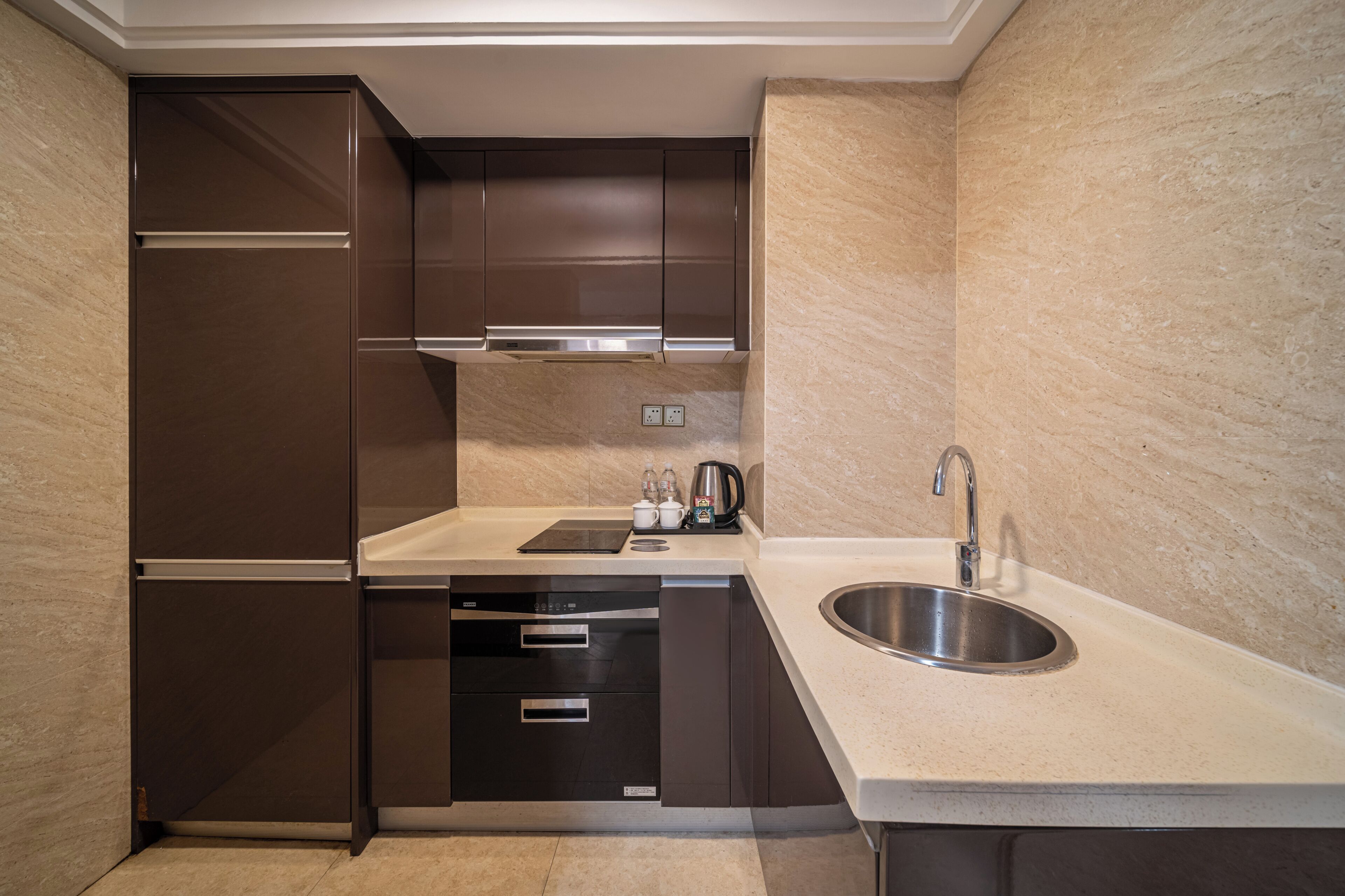 A modern kitchen with dark cabinetry, a stainless steel sink, and a built-in oven.