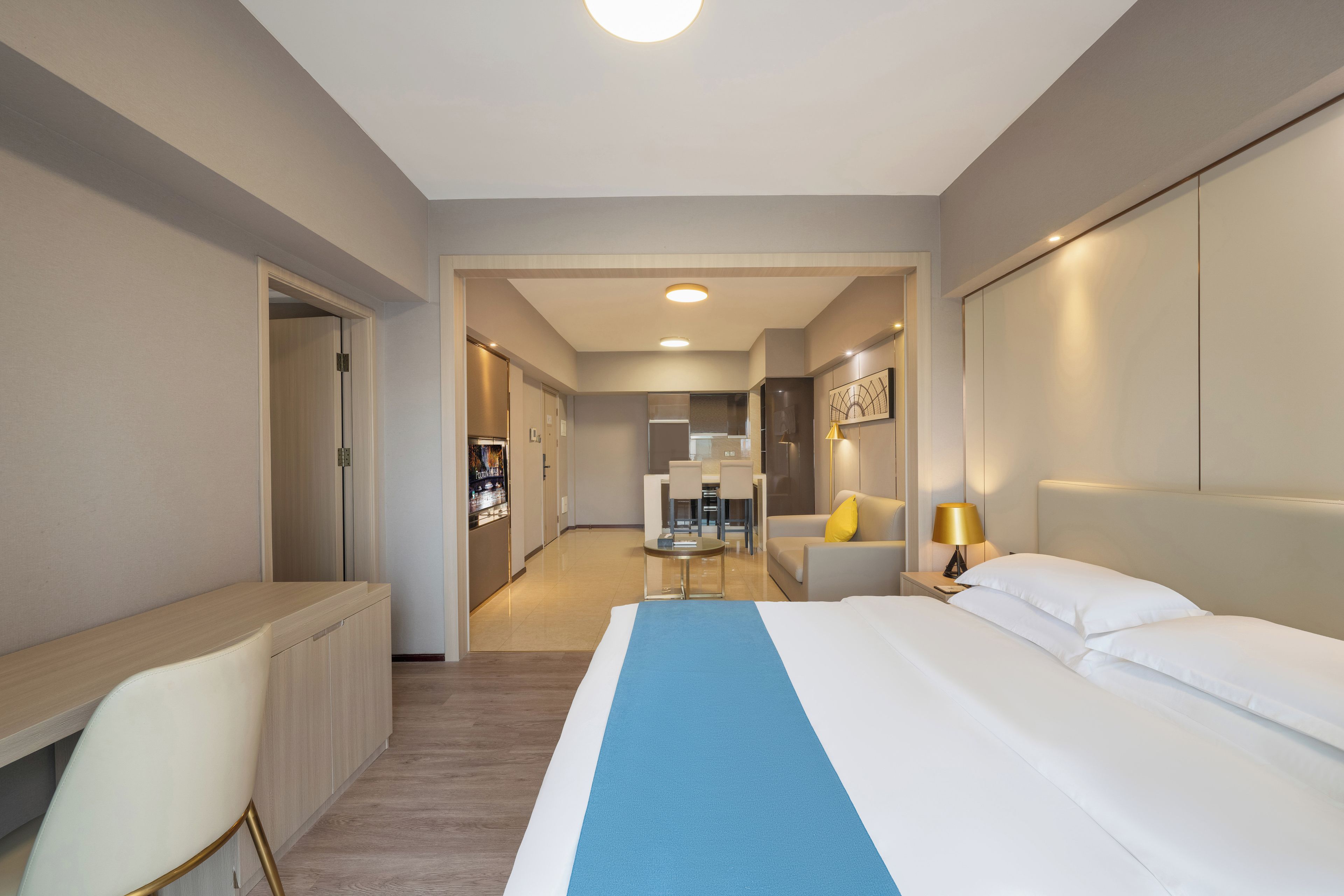 Una camera d'albergo con un letto, una scrivania, una sedia, un divano e un tavolino con una lampada.