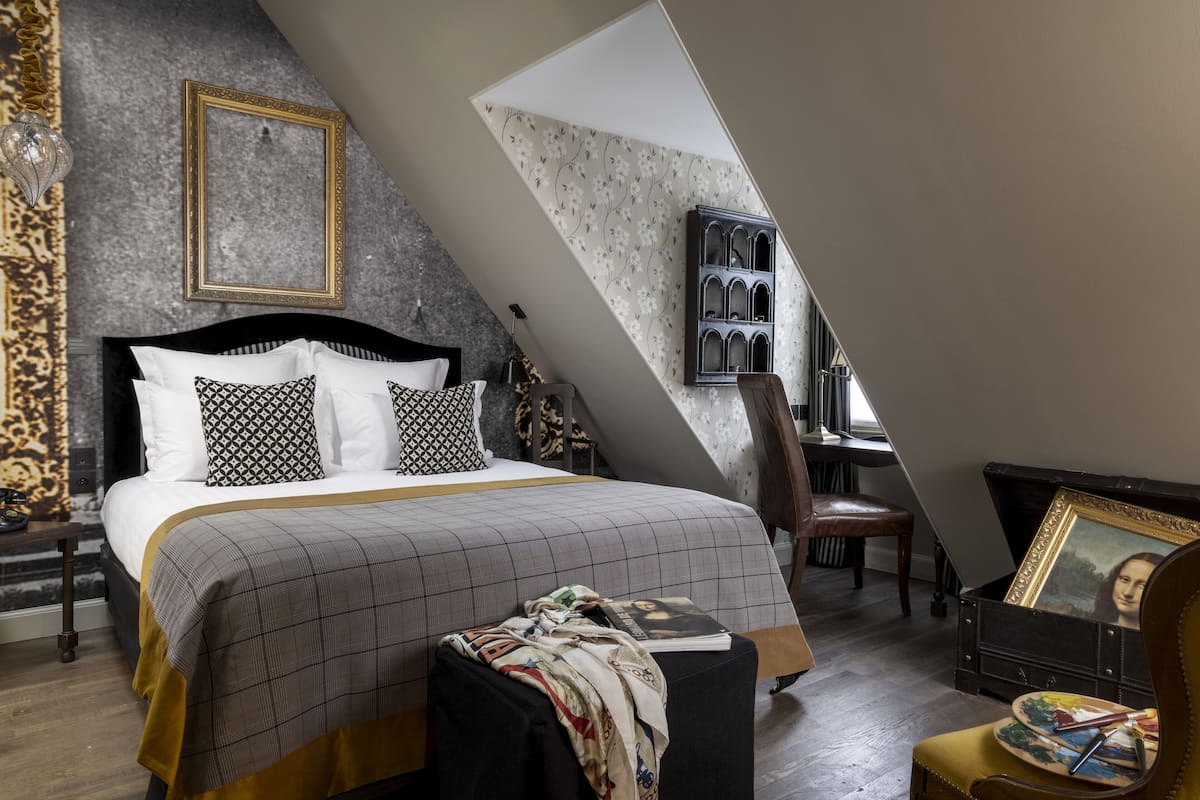 A bedroom with a large bed, a dresser, a chair, and a painting on the wall.