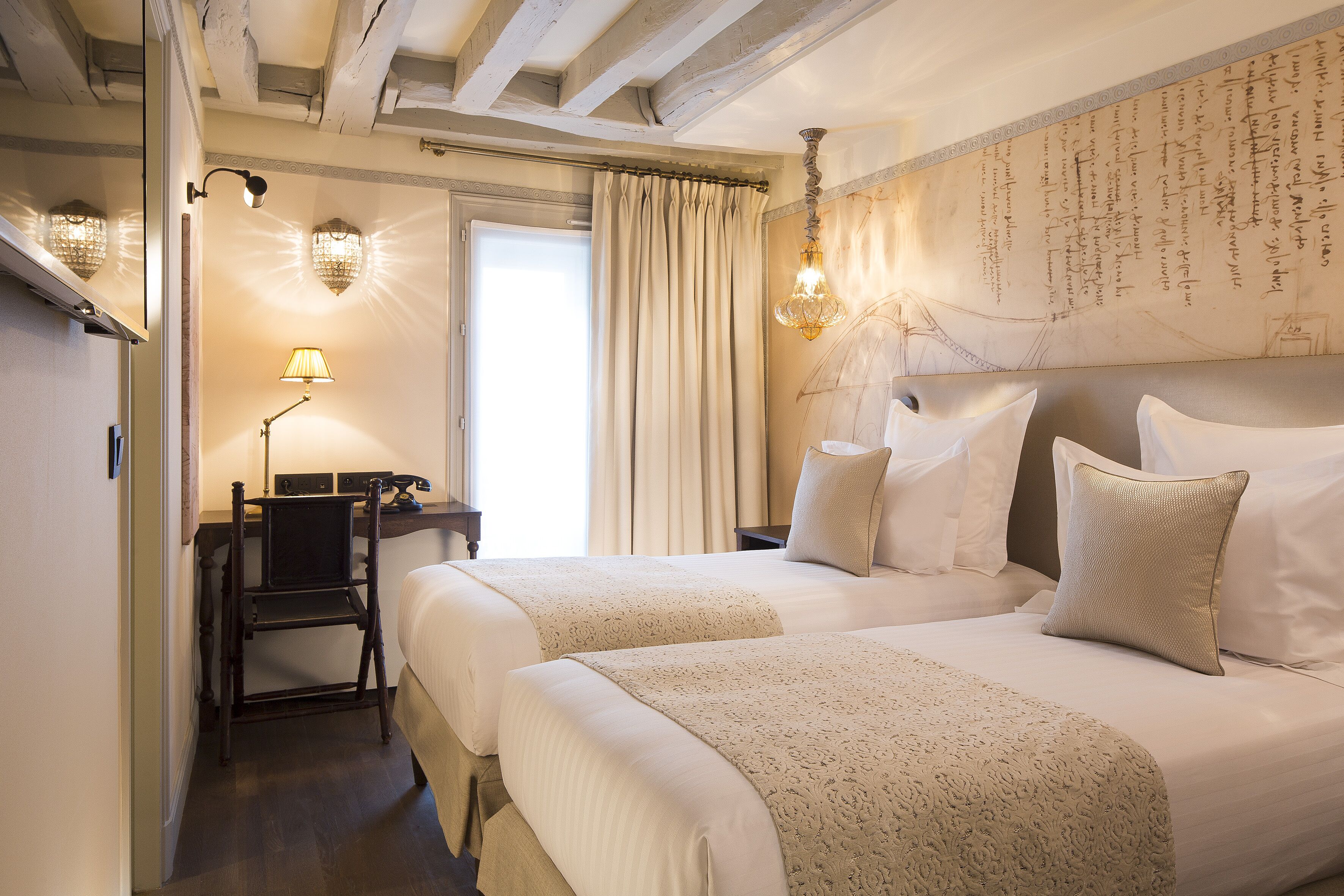 Une chambre d’hôtel avec deux lits, un bureau et une grande fenêtre avec des rideaux.