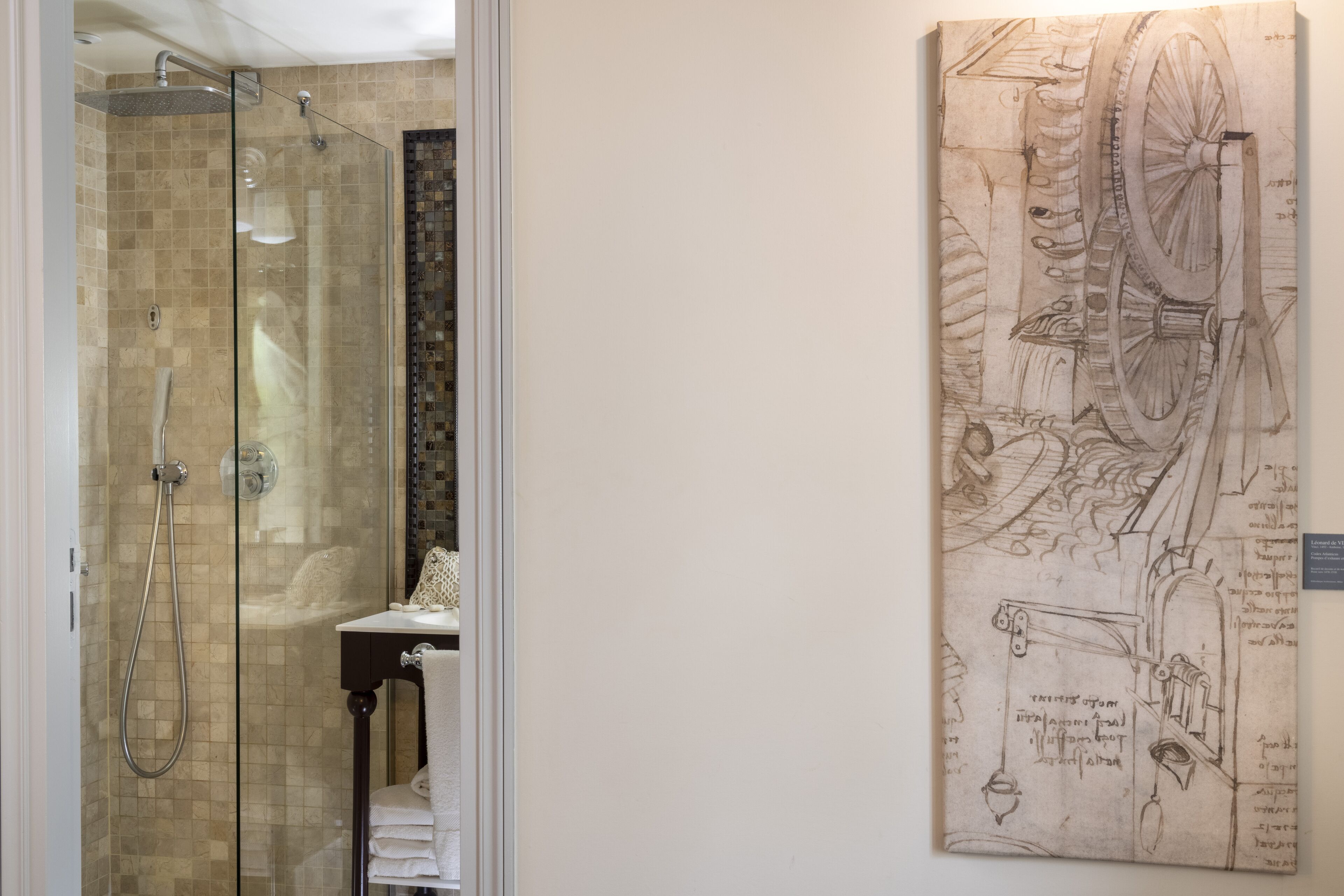 A bathroom with a glass-enclosed shower, a sink with a towel, and a wall-mounted toilet.
