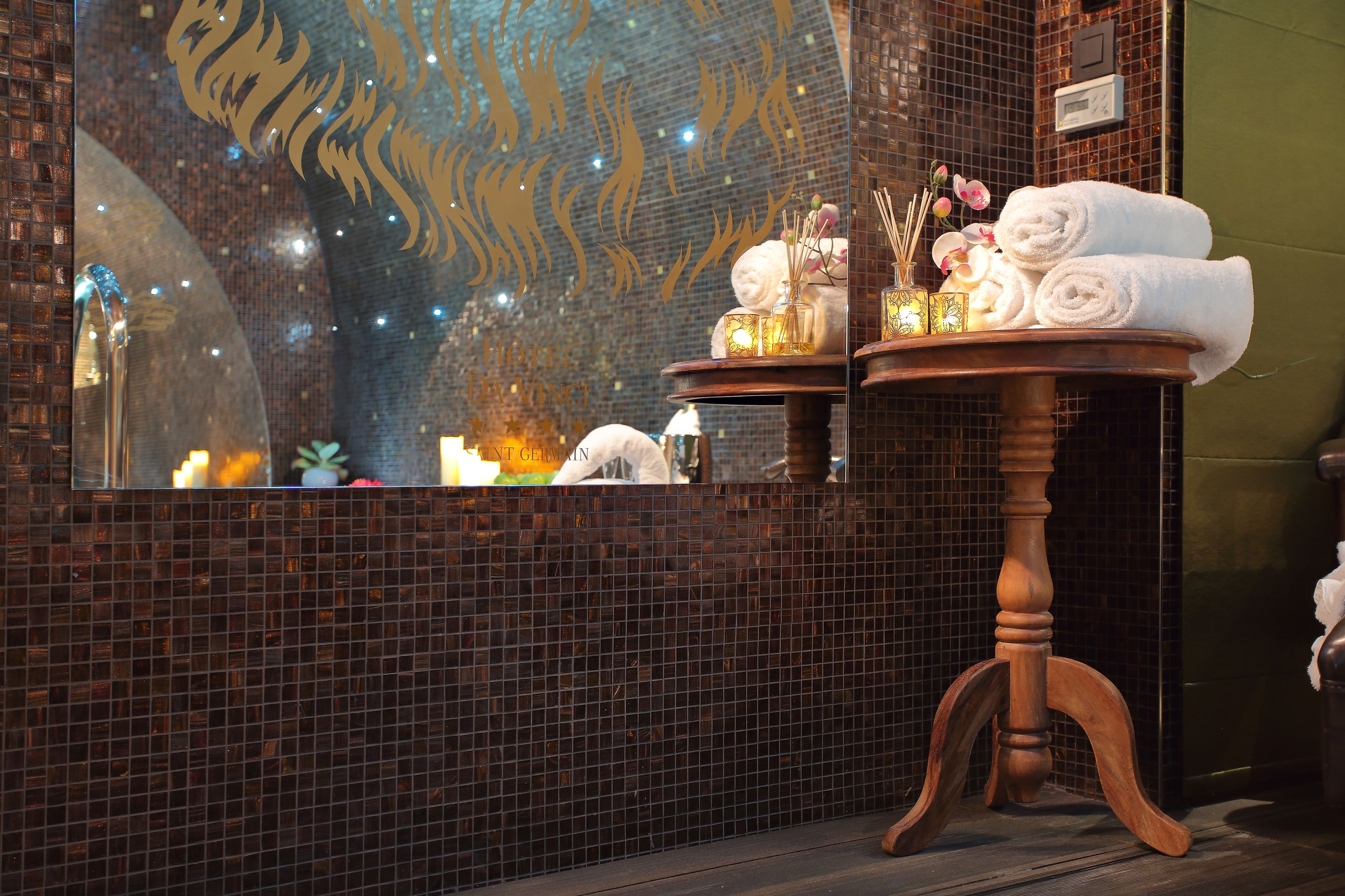 A bathroom with a mirror, a wooden table with towels, and decorative items.