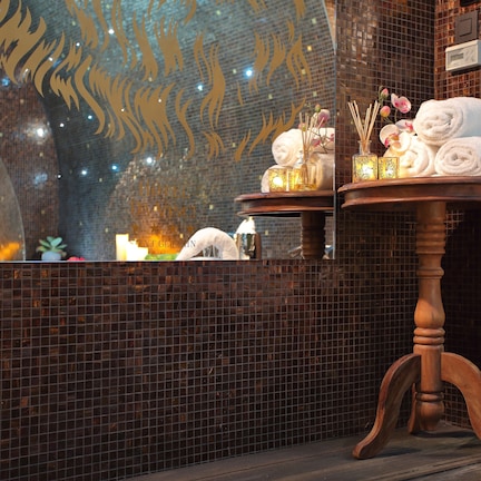A bathroom with a mirror, a wooden table with towels, and decorative items.