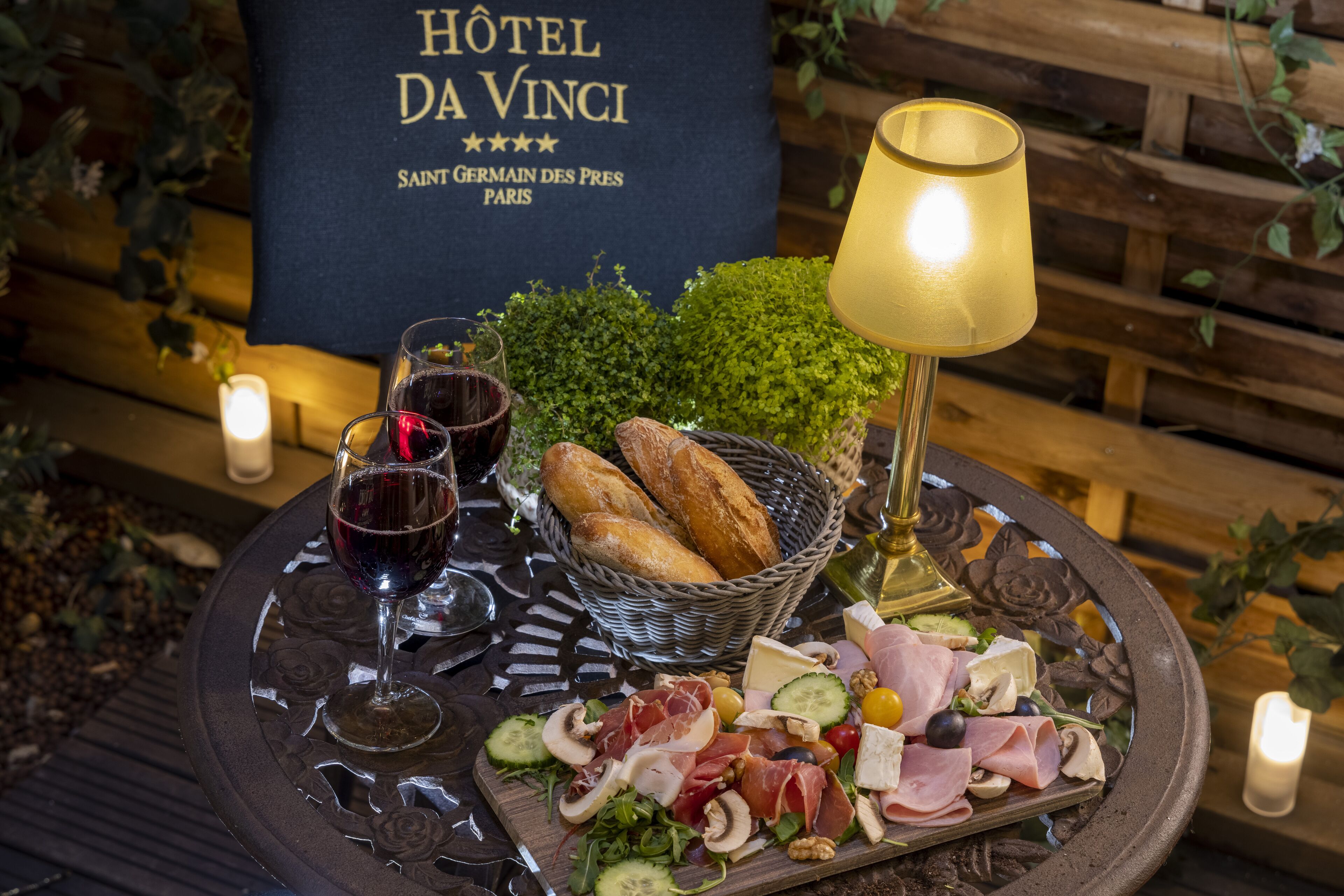 A table with a charcuterie board, wine glasses, and a lamp.