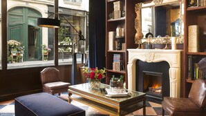 Una habitación acogedora con chimenea, estanterías, un sillón de cuero y vista a la calle.