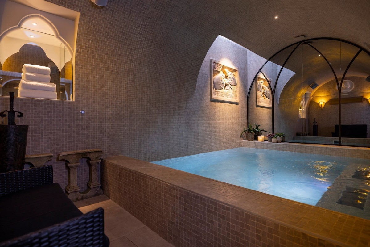 A spa area with a hot tub, tiled walls, and framed artwork.