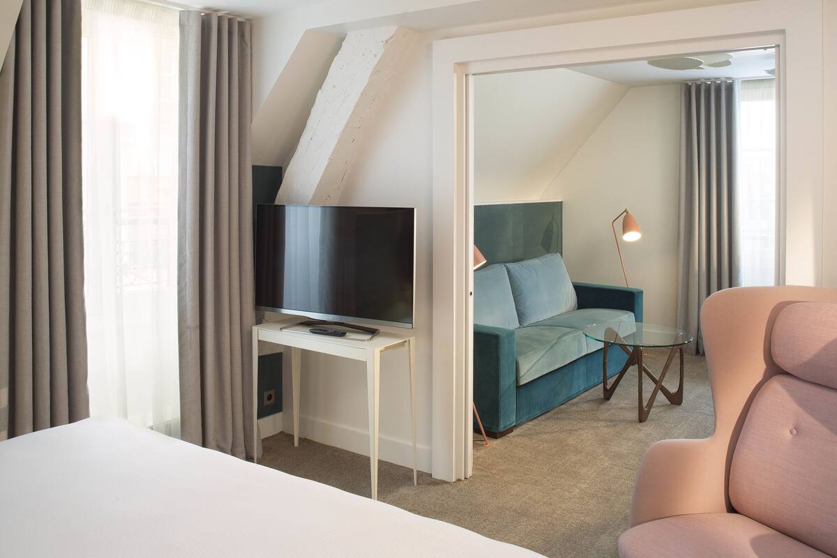 Une chambre d’hôtel avec un lit, un bureau avec une télévision, un canapé et une lampe.