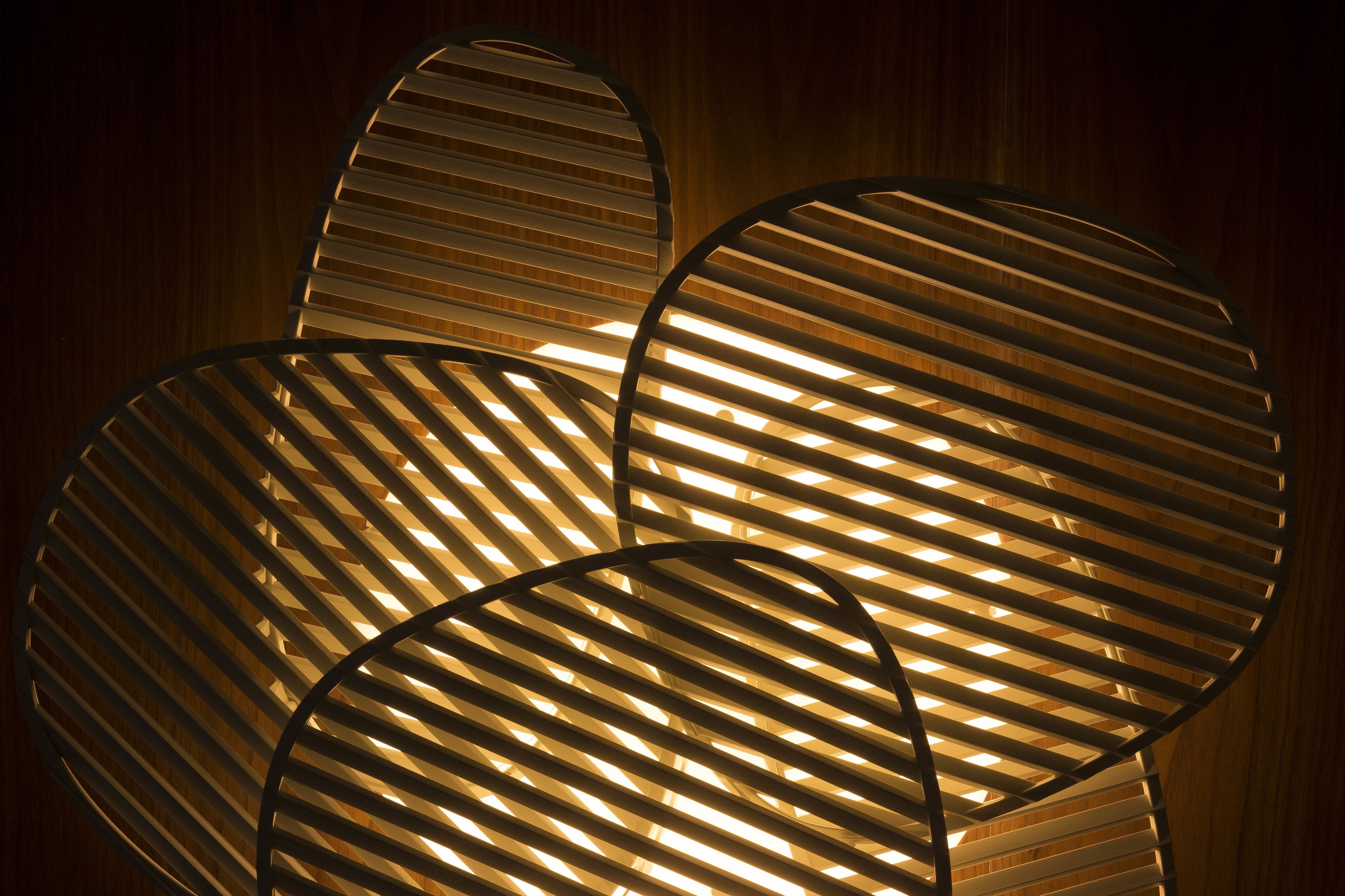 Een moderne, ronde lamp met horizontale lamellen, voor een houten achtergrond.