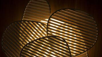 Een moderne, ronde lamp met horizontale lamellen, voor een houten achtergrond.