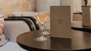 A round table with a glass of champagne and a brown sign labeled "DUPOND HILMS". - Hôtel Dupond Smith (Paris)