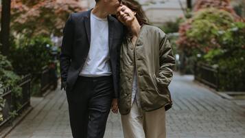Una pareja camina por un sendero pavimentado, flanqueado por follaje.