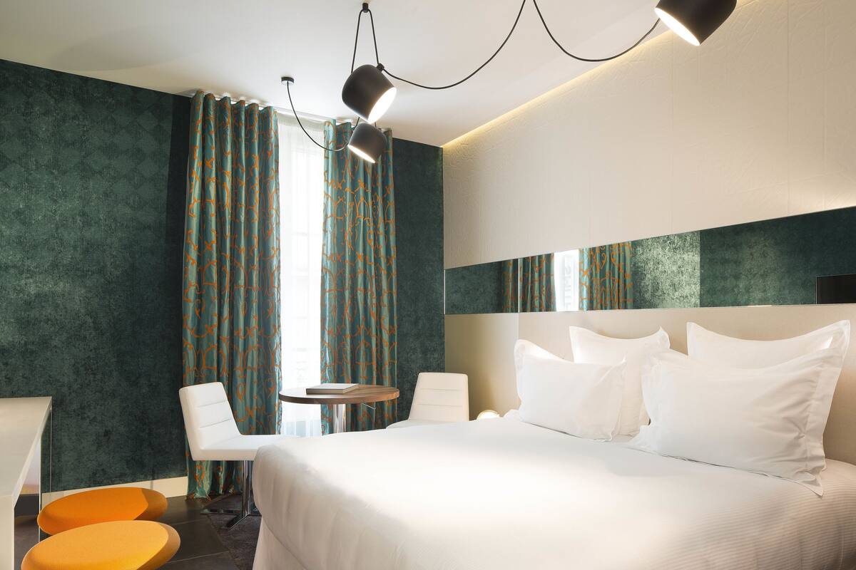 Une chambre d’hôtel moderne avec un grand lit, un bureau, deux chaises et une petite table.
