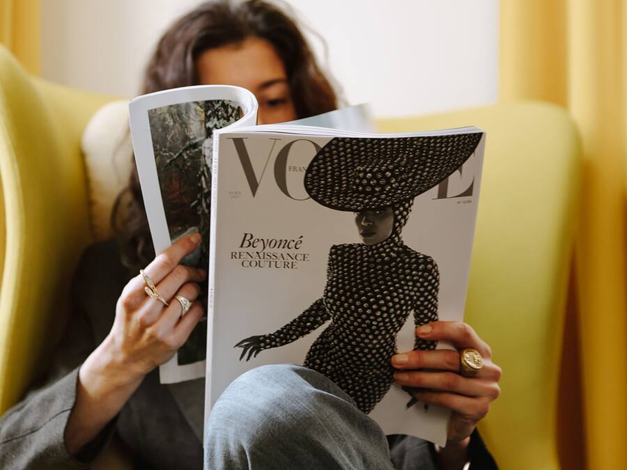 Una persona sentada en una silla amarilla leyendo una revista.