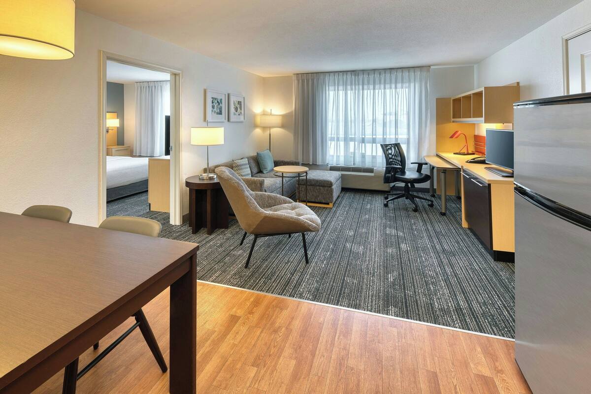 Une chambre d’hôtel comprenant un lit, un canapé, un bureau avec un ordinateur, une chaise et une table à manger.