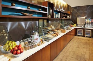 Un bufé con diferentes opciones de comida, como frutas, pasteles y bebidas.