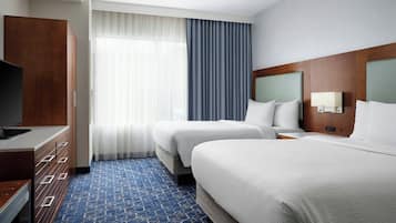 Een hotelkamer met twee bedden, een televisie, een houten garderobe en een groot raam met gordijnen.