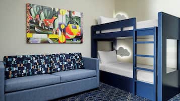 A room with a bunk bed, a sofa, and a colorful abstract painting on the wall.