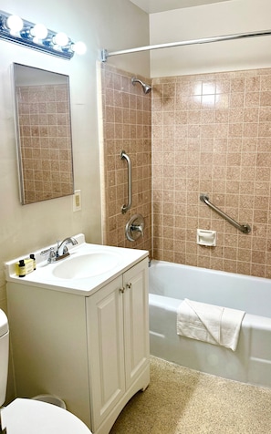 A bathroom with a sink, mirror, and shower area.