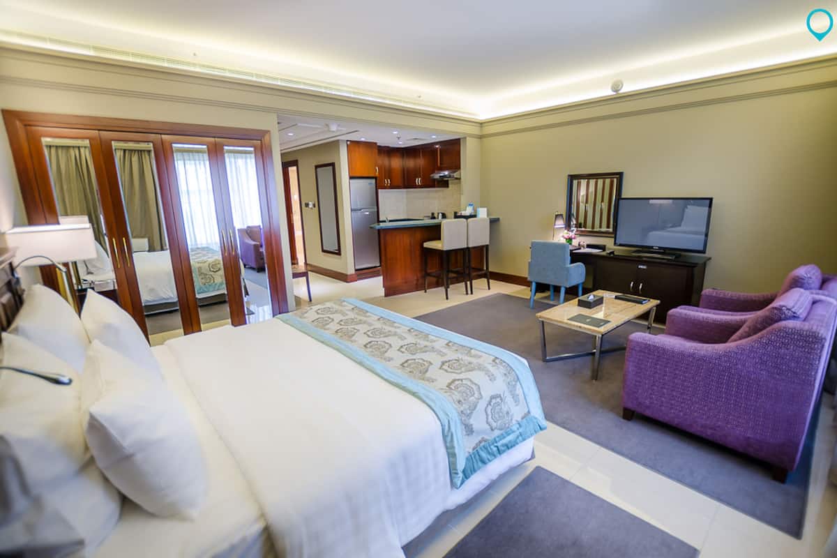 Ein Hotelzimmer mit einem Bett, einem Schreibtisch, einem Fernseher und einem violetten Sessel.