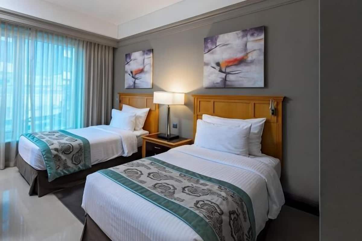 Ein Hotelzimmer mit zwei Betten, einem Nachttisch mit Lampe und Bildern an der Wand.
