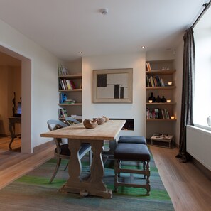 Ein Essbereich mit Holztisch, zwei Stühlen, einer Bank, einem Bücherregal und einem Kamin.