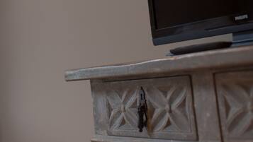 A television on a wooden cabinet with a wall-mounted lamp.