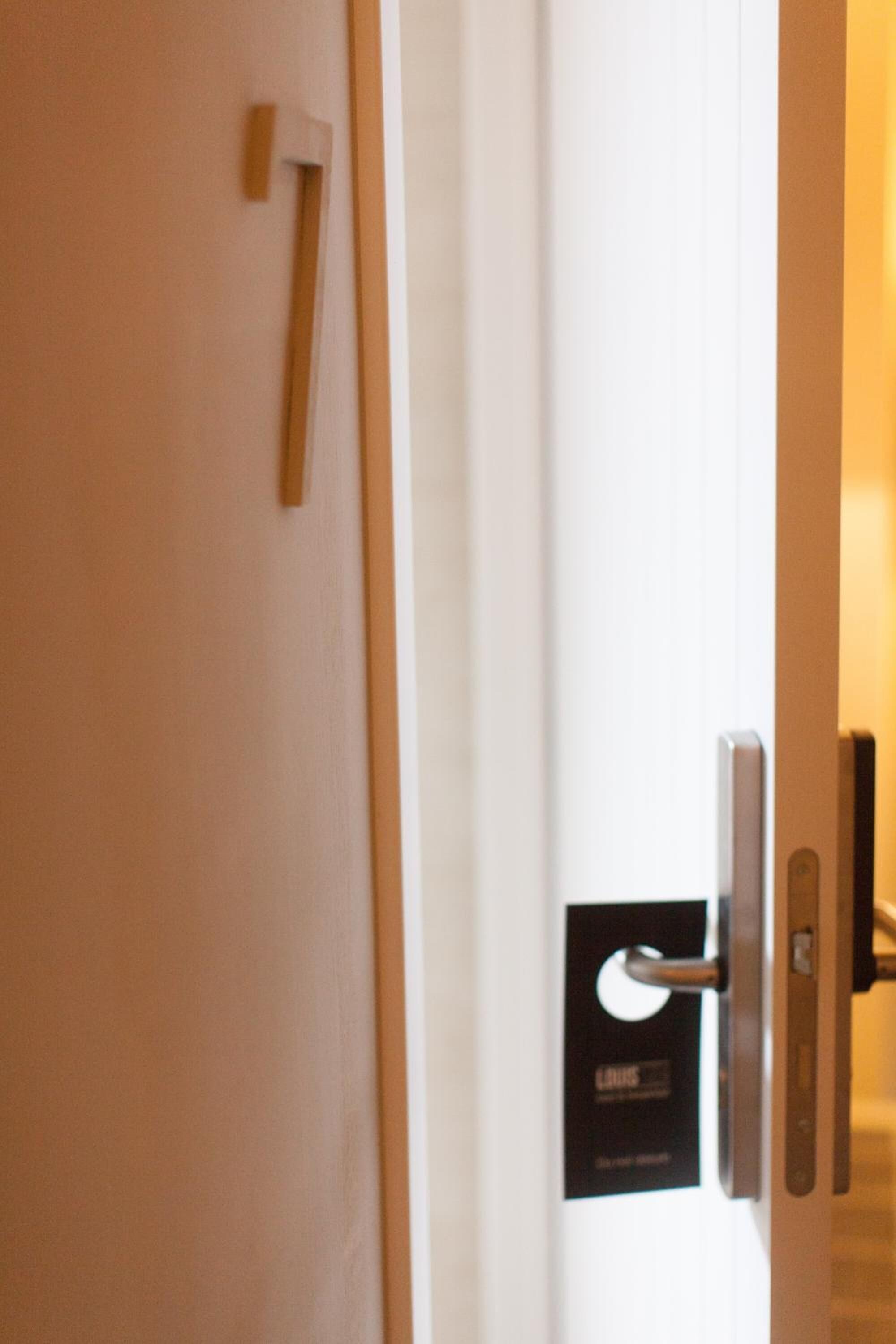 En hotellrumsdörr med ett numeriskt kodlås och en skylt som visar rummets nummer.