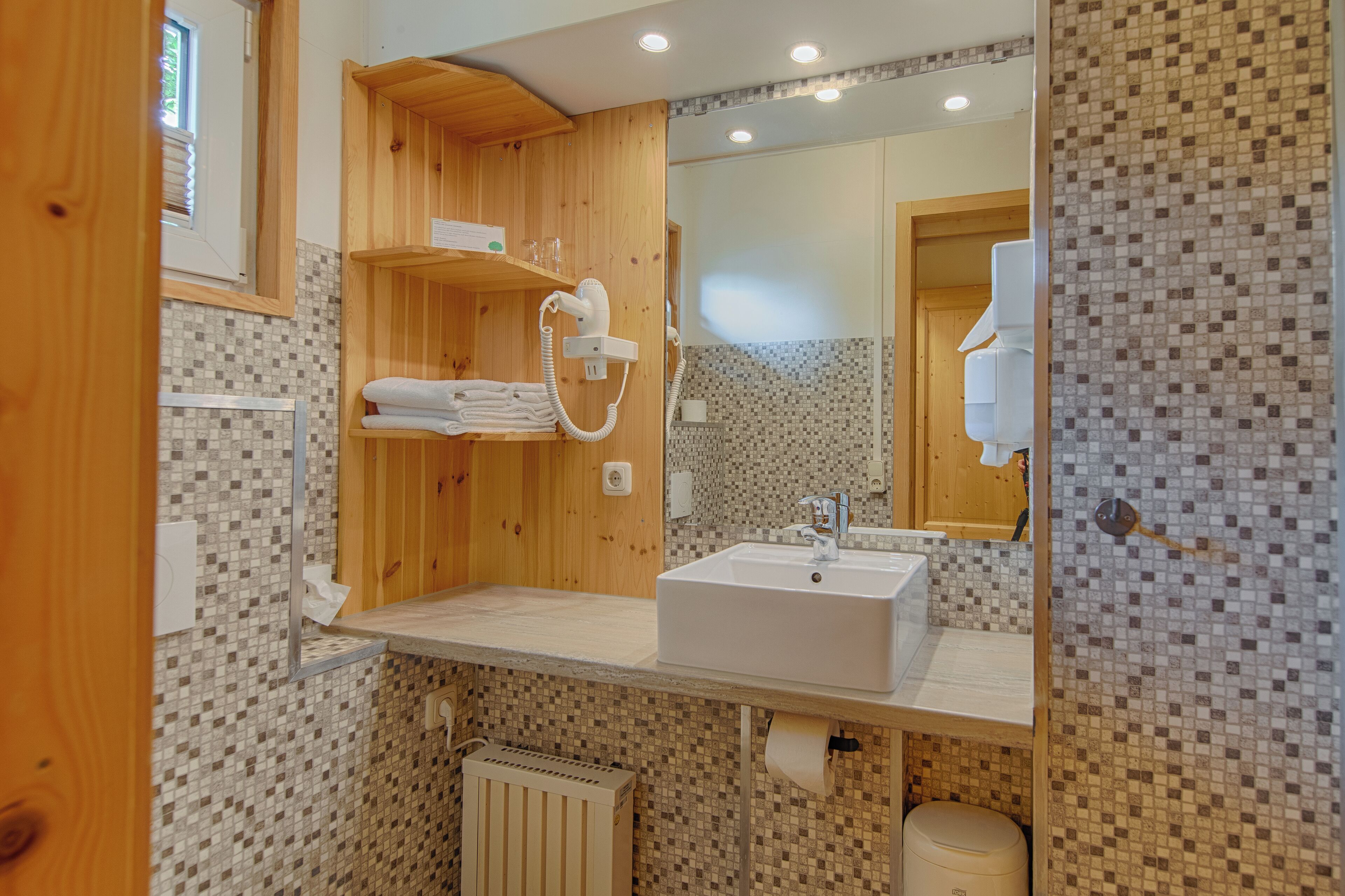A modern bathroom with a wooden vanity, a sink, and a tiled backsplash.