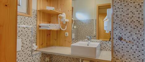 A modern bathroom with a wooden vanity, a sink, and a tiled backsplash.