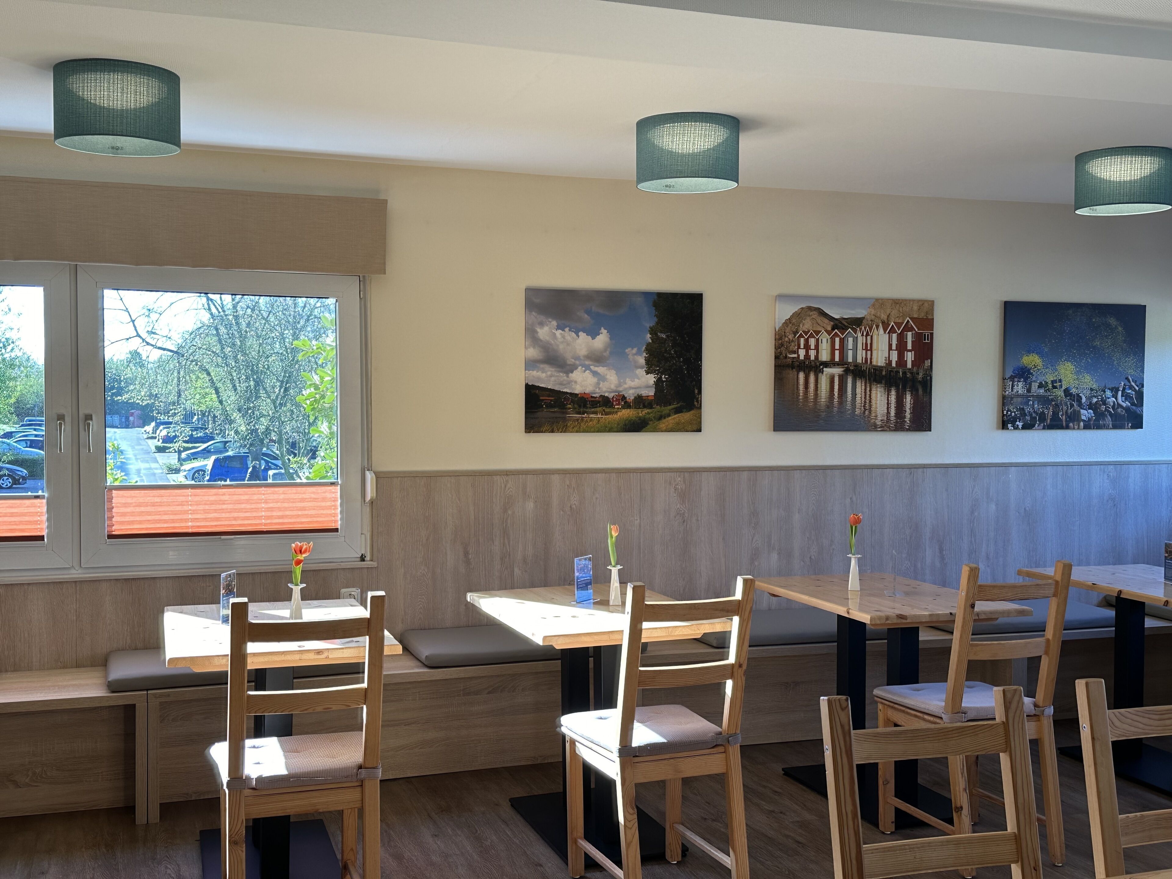 A restaurant interior with wooden furniture, a bench seating area, and artwork on the walls.