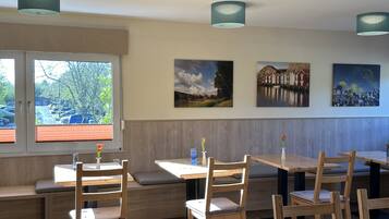 A restaurant interior with wooden furniture, a bench seating area, and artwork on the walls.
