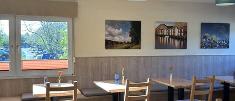 A restaurant interior with wooden furniture, a bench seating area, and artwork on the walls.