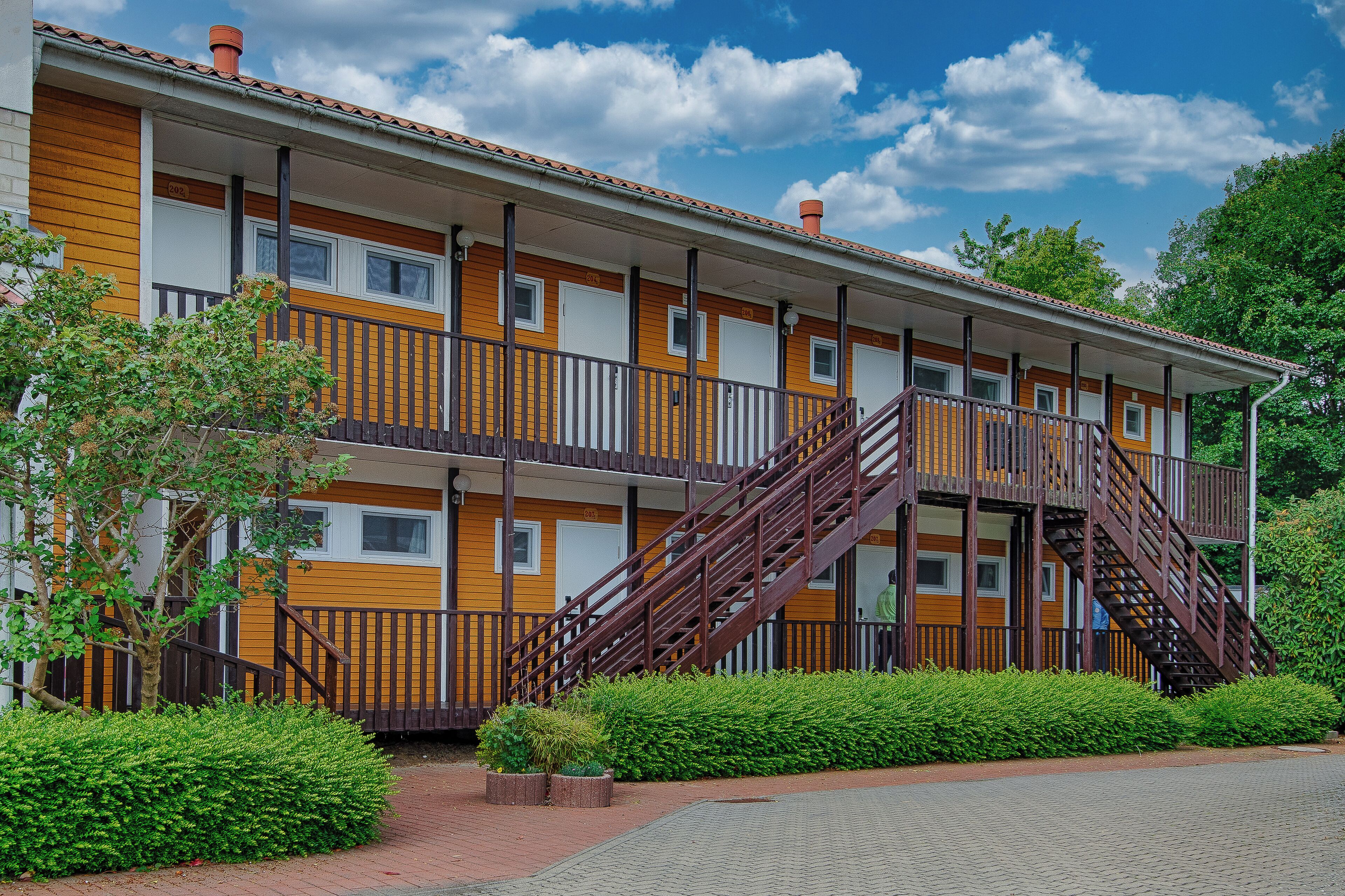 A multi-story hotel with a central staircase, balconies, and a brick pathway.