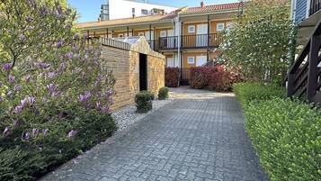 A paved pathway leading to a building with a wooden facade and a balcony.