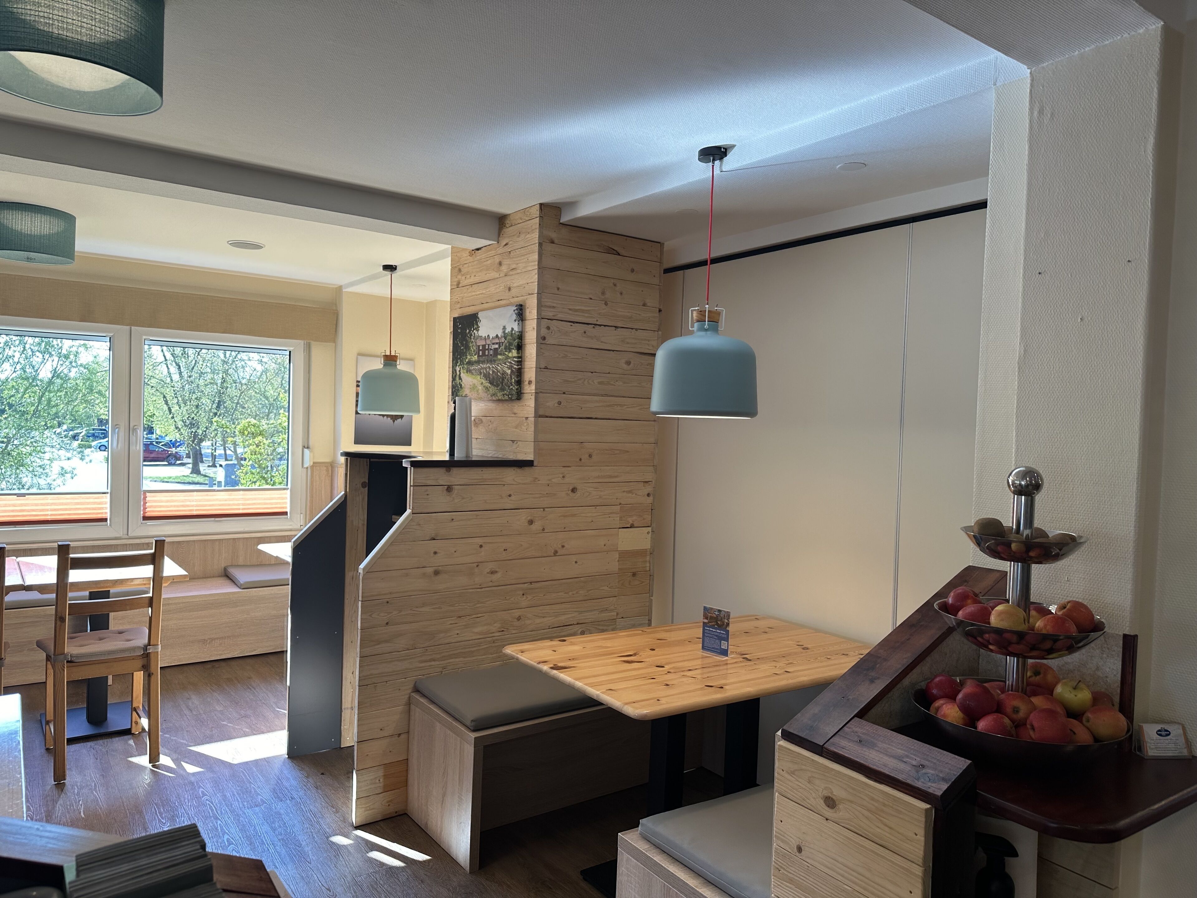 Un interior moderno con una pared de acento de madera, una mesa de madera con un banco y una exhibición de frutas.