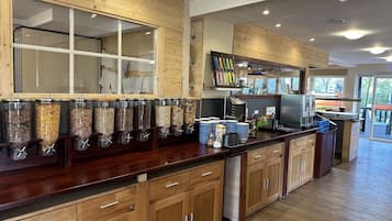 A modern kitchen with wooden cabinets, a central island with a coffee machine, and a window overlooking a deck.